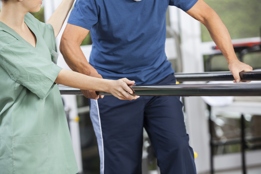 Physiotherapist,Standing,By,Senior,Man,Walking,Between,Parallel