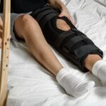 Female,Patient,Wearing,Orthosis,Sitting,On,Bed,Holding,Crutches,After