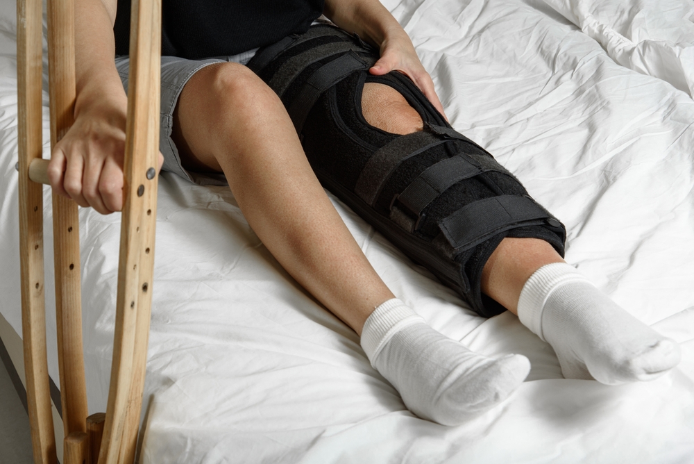 Female,Patient,Wearing,Orthosis,Sitting,On,Bed,Holding,Crutches,After